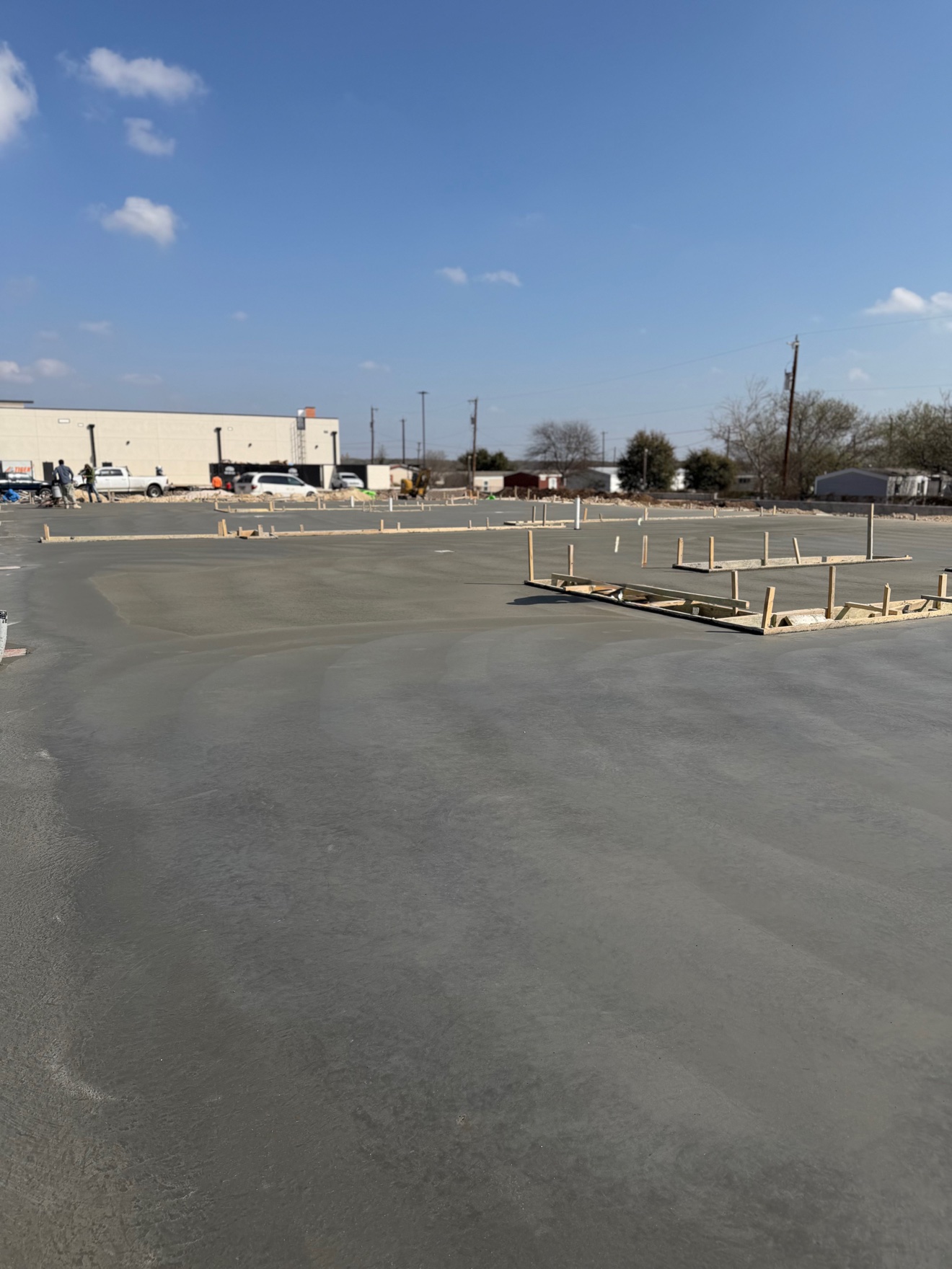 Large freshly poured concrete slab stretching across the job site
