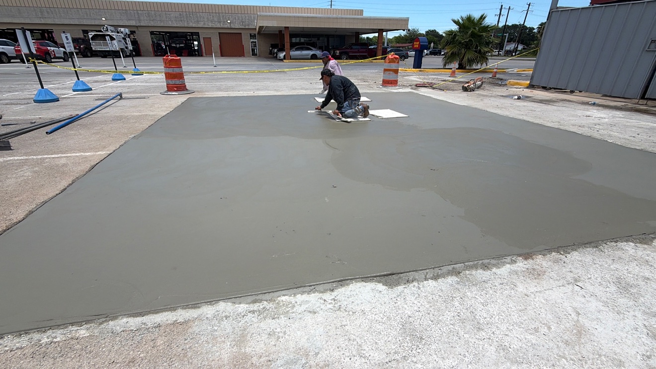 Crew member hand-finishing a fresh concrete parking lot repair panel