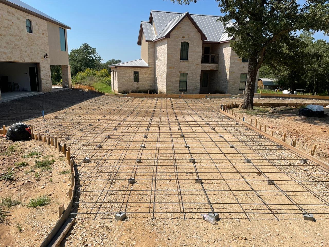 Driveway prepped with a rebar grid in front of a stone house