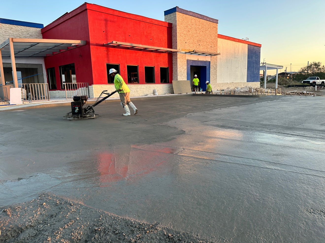 Crew member power-trowel finishing a fresh concrete lot