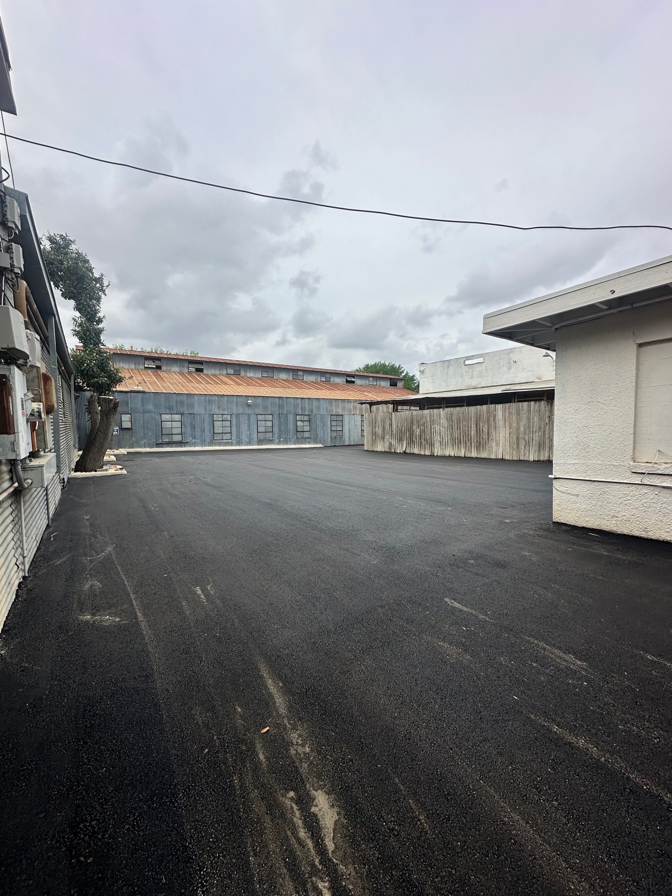 Freshly paved asphalt lot beside a metal warehouse building