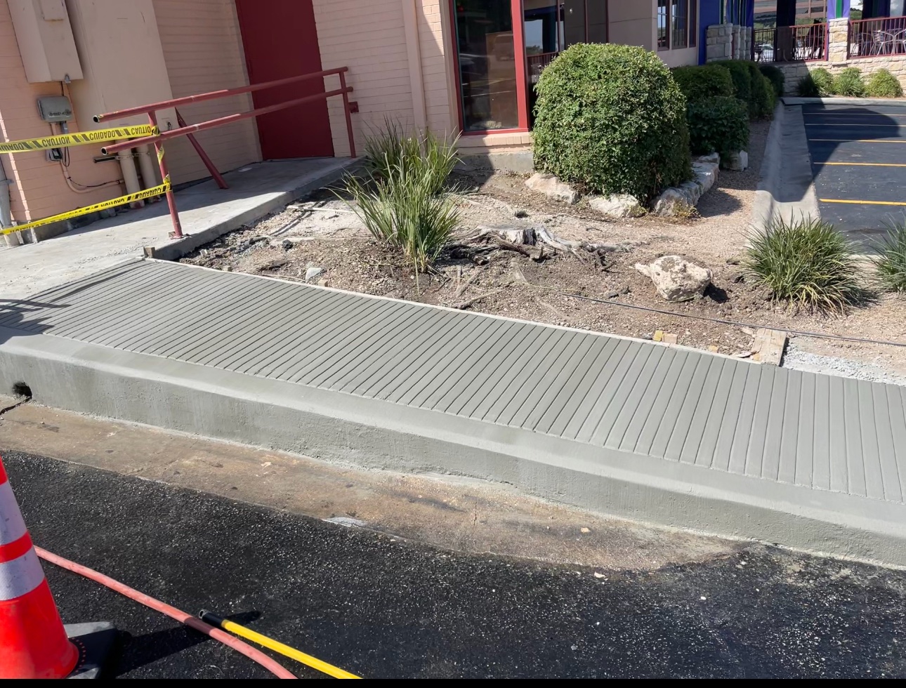 Newly poured concrete ADA ramp with grooved surface at a commercial building