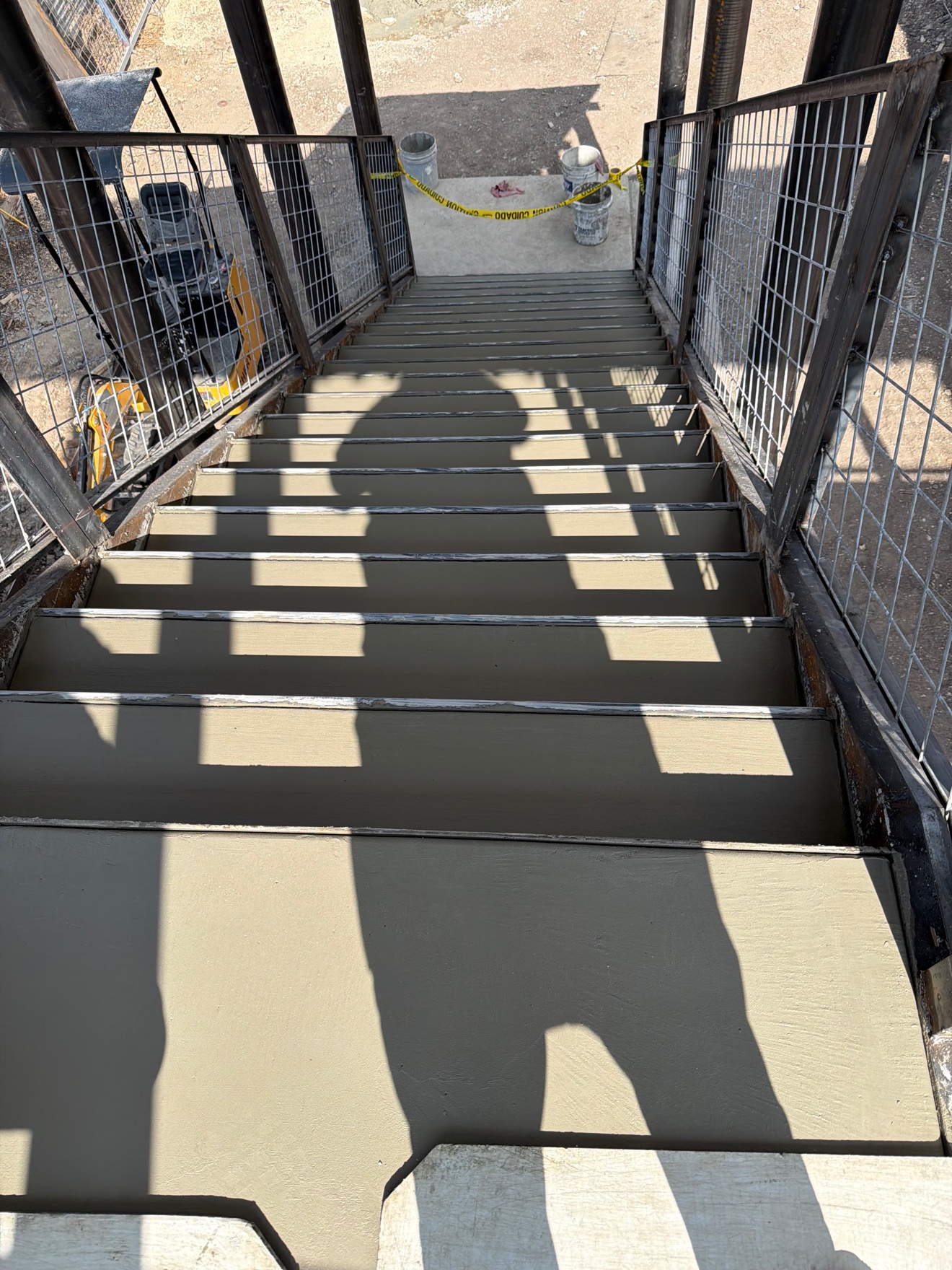 Freshly poured concrete stairs with metal railings, viewed from the top