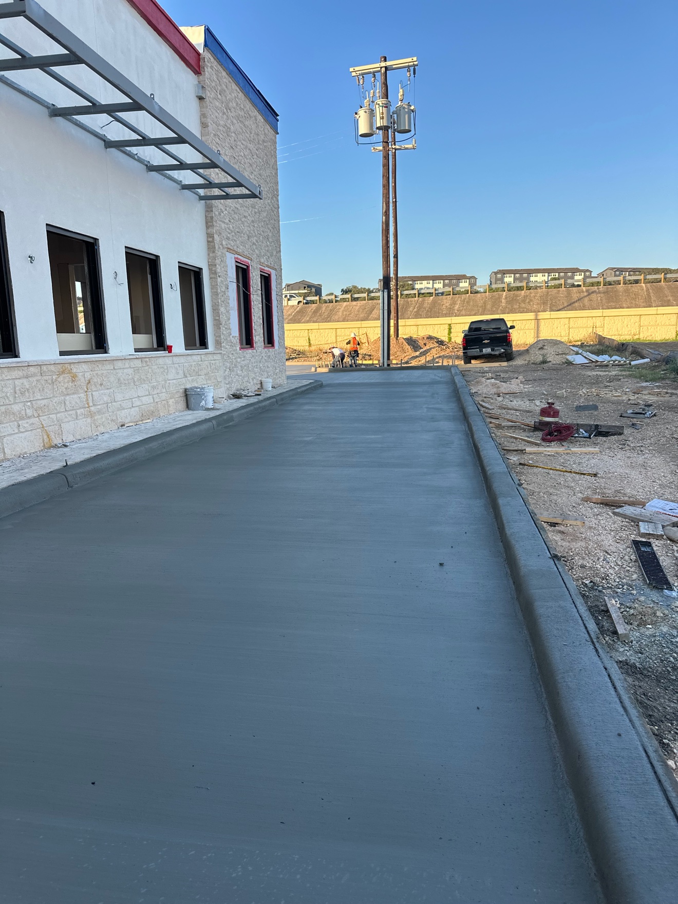 Freshly poured concrete drive lane and curb beside a commercial building