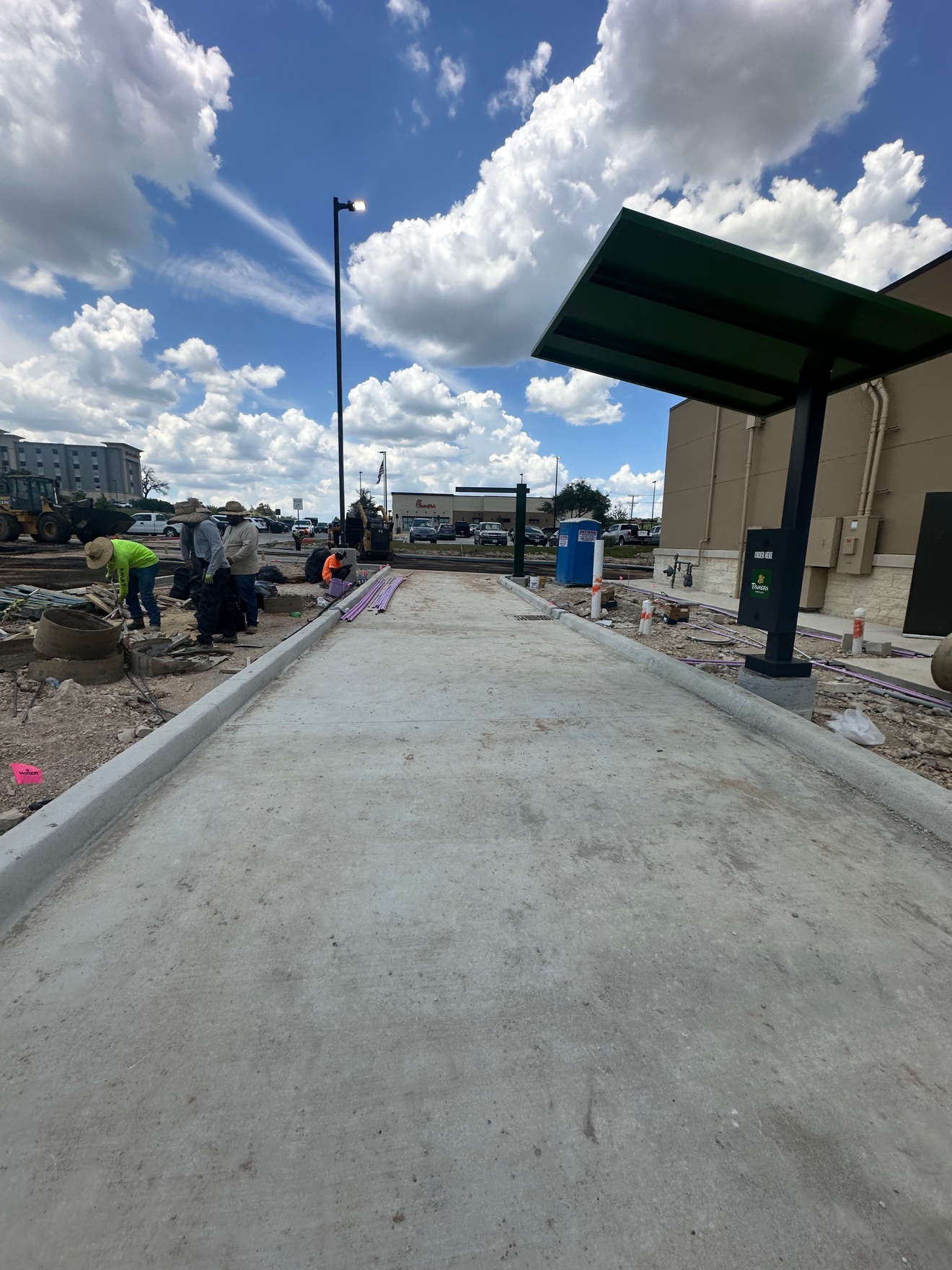 Concrete drive-thru lane at Panera Bread with crew working alongside