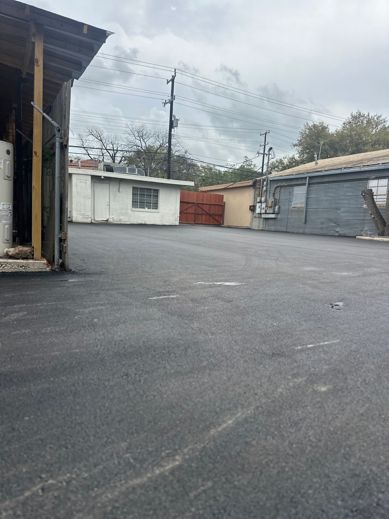 Freshly paved asphalt yard between small commercial buildings