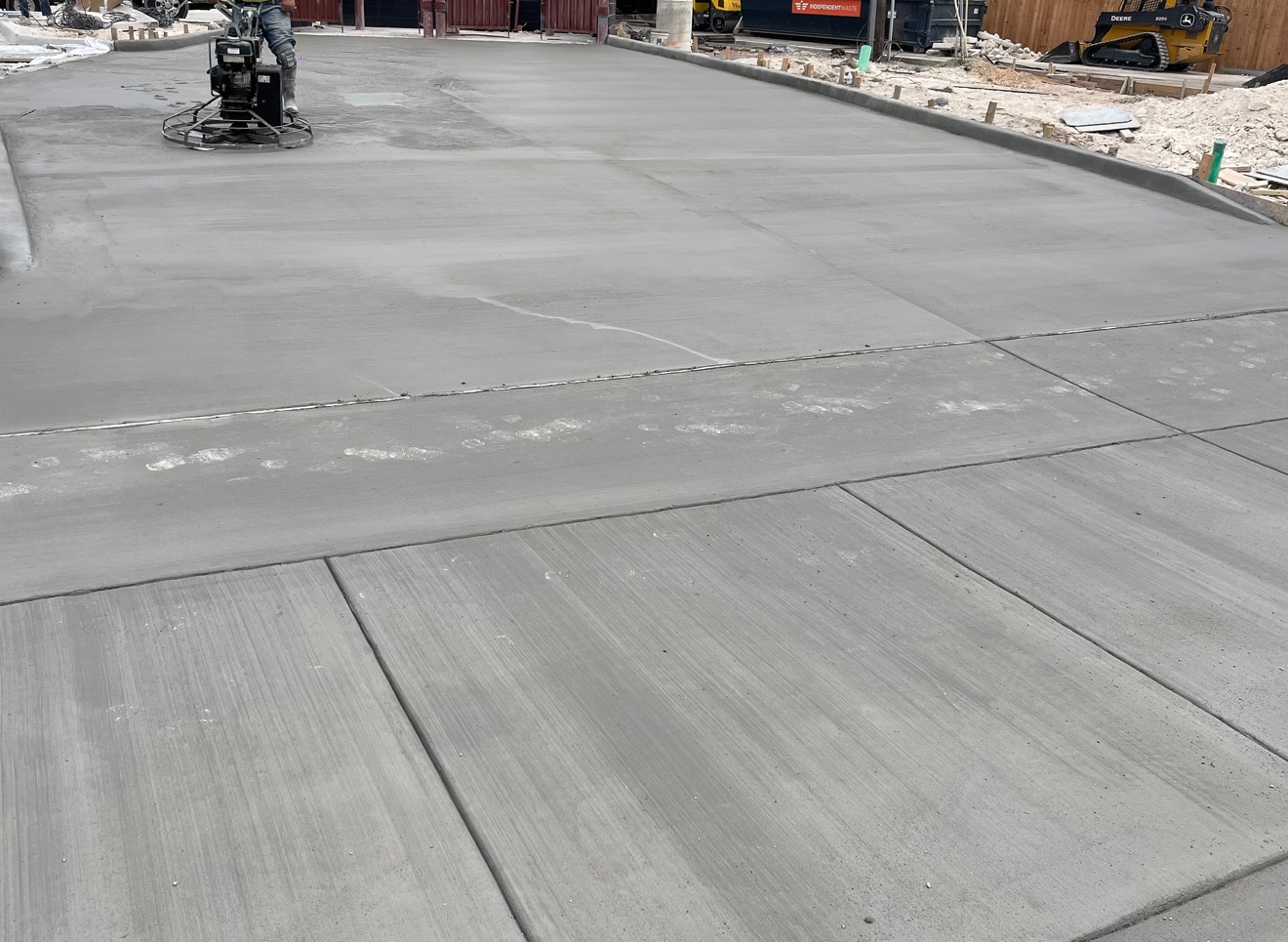 Crew finishing a freshly poured concrete slab with a power trowel