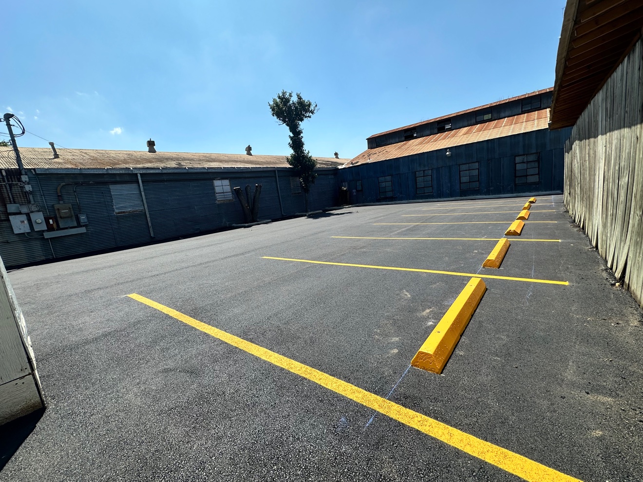 Fresh yellow parking lot striping and wheel stops on new asphalt