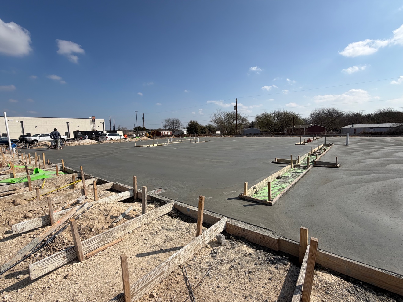 Large concrete slab pour with formwork and a grade beam trench in the foreground