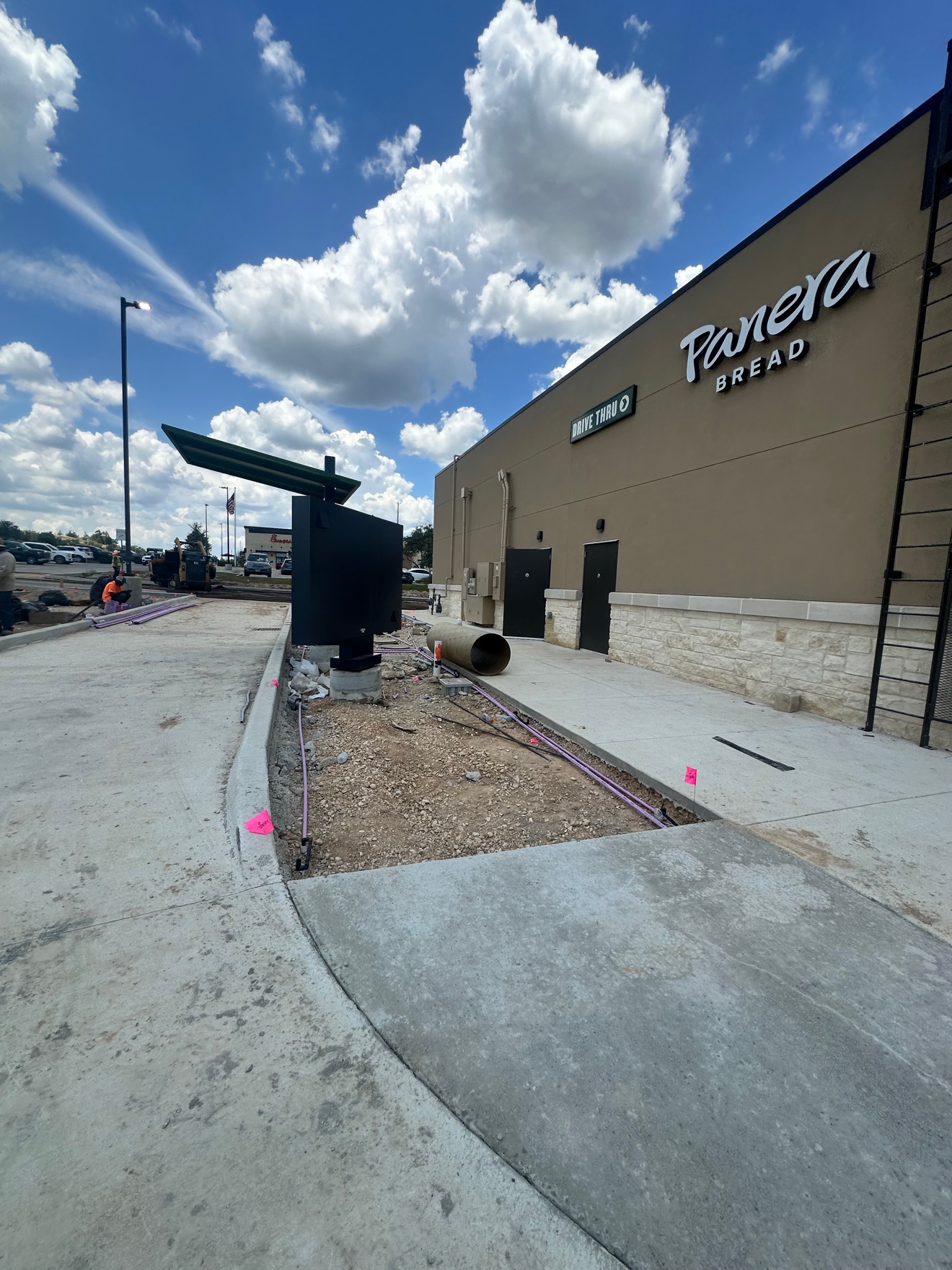 Concrete sidewalk and drive-thru lane beside the Panera Bread building