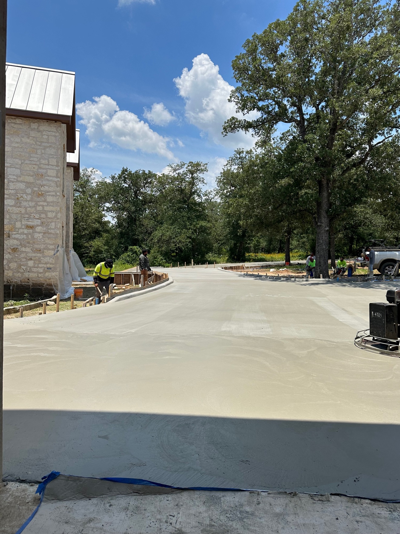 Finished curved concrete driveway in front of a stone house
