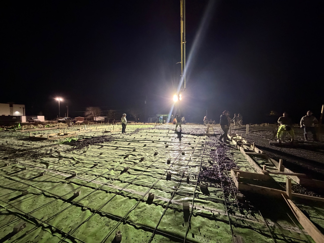 Night concrete pour with a pump boom placing concrete over rebar and vapor barrier