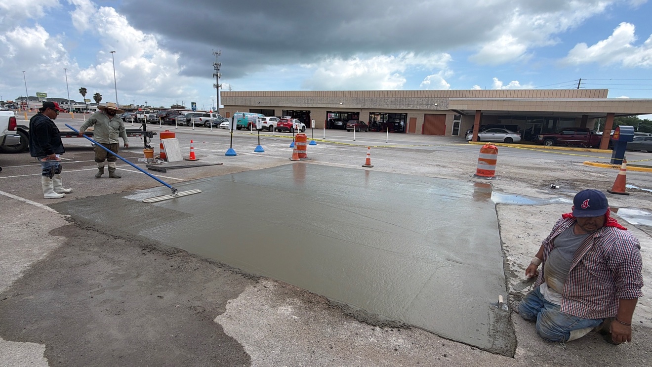 Crew floating a freshly poured concrete parking lot repair panel