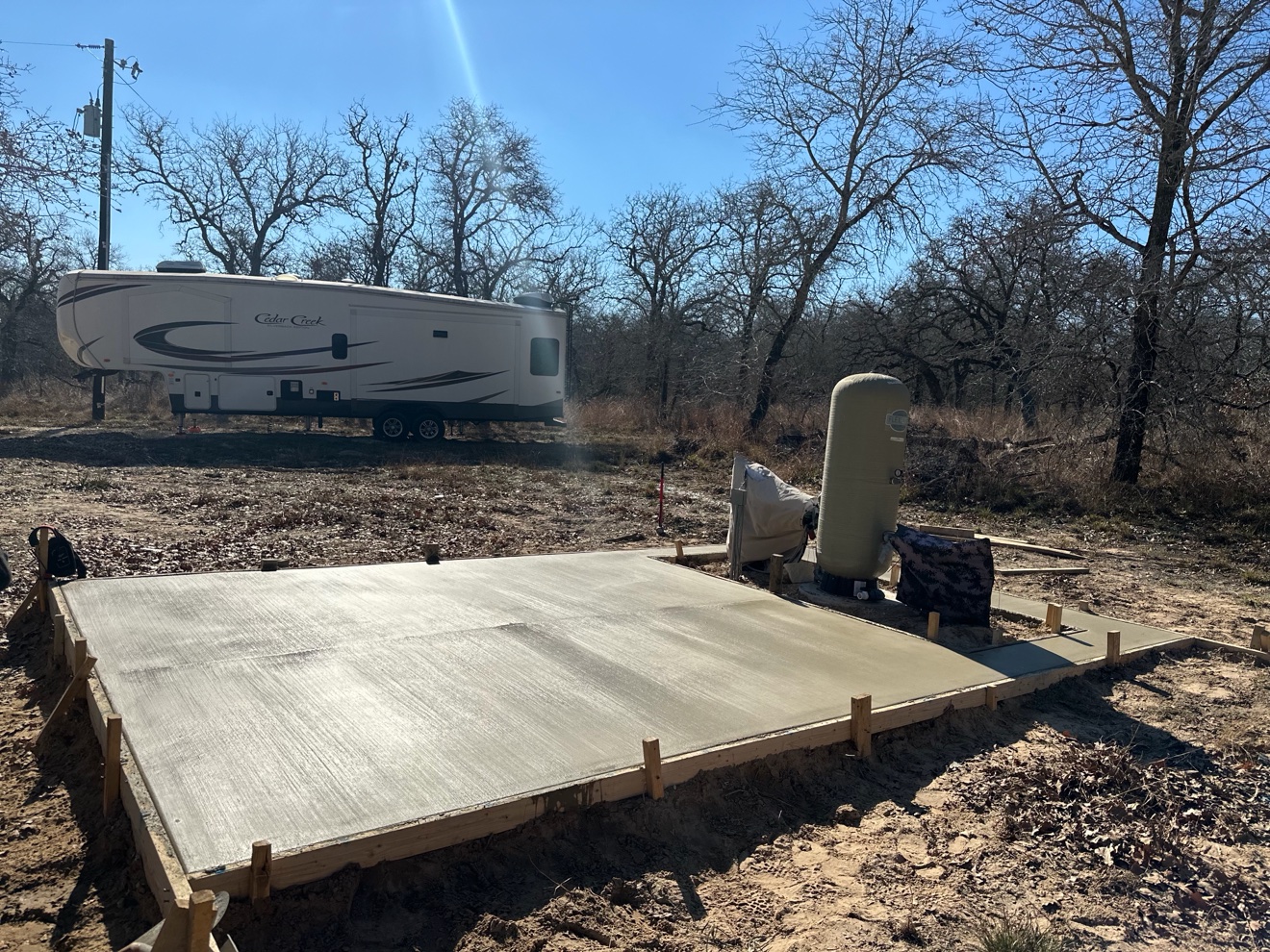 Finished concrete RV pad with an RV parked behind it