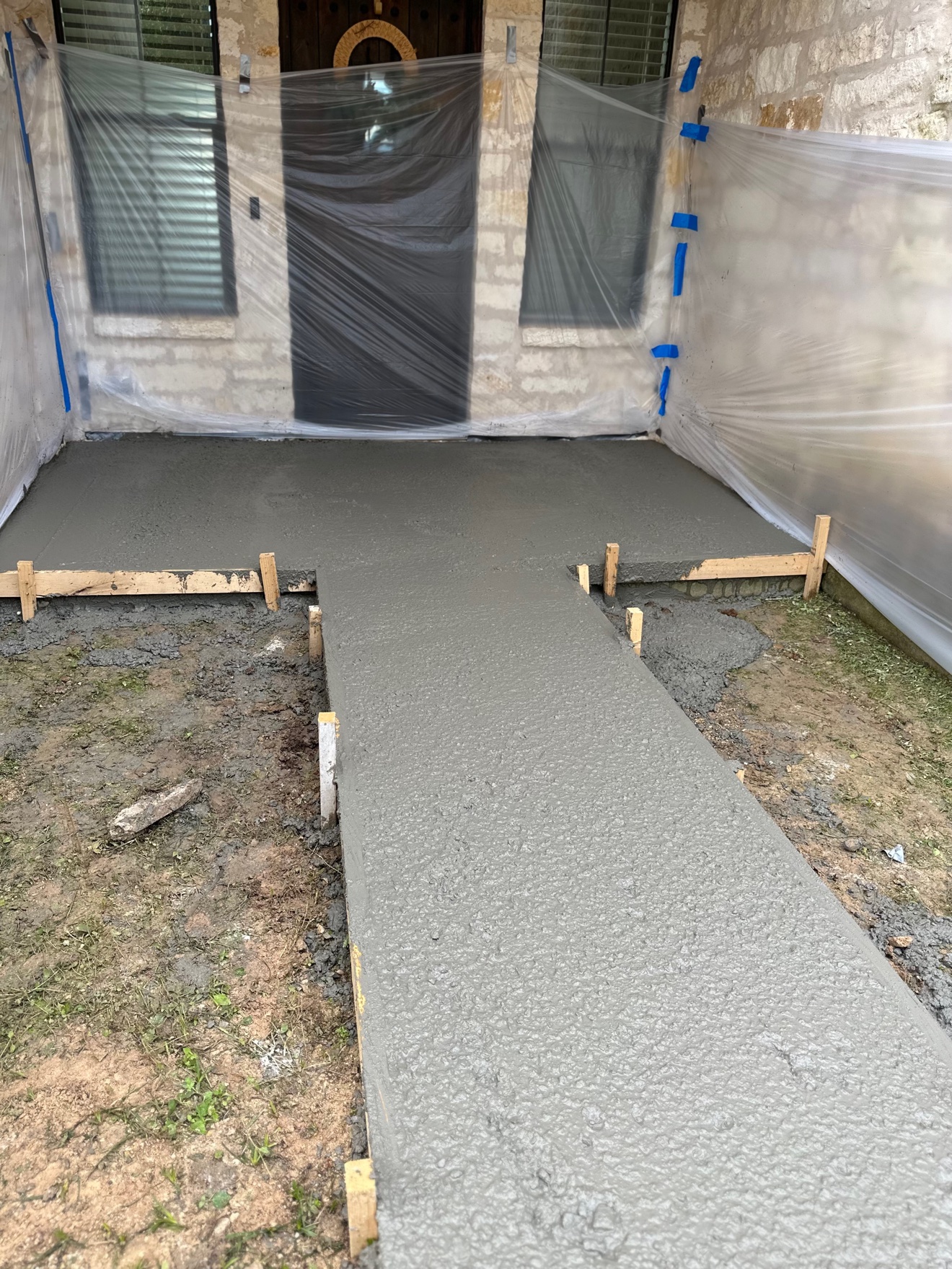 Freshly poured concrete porch and walkway at a stone house entrance