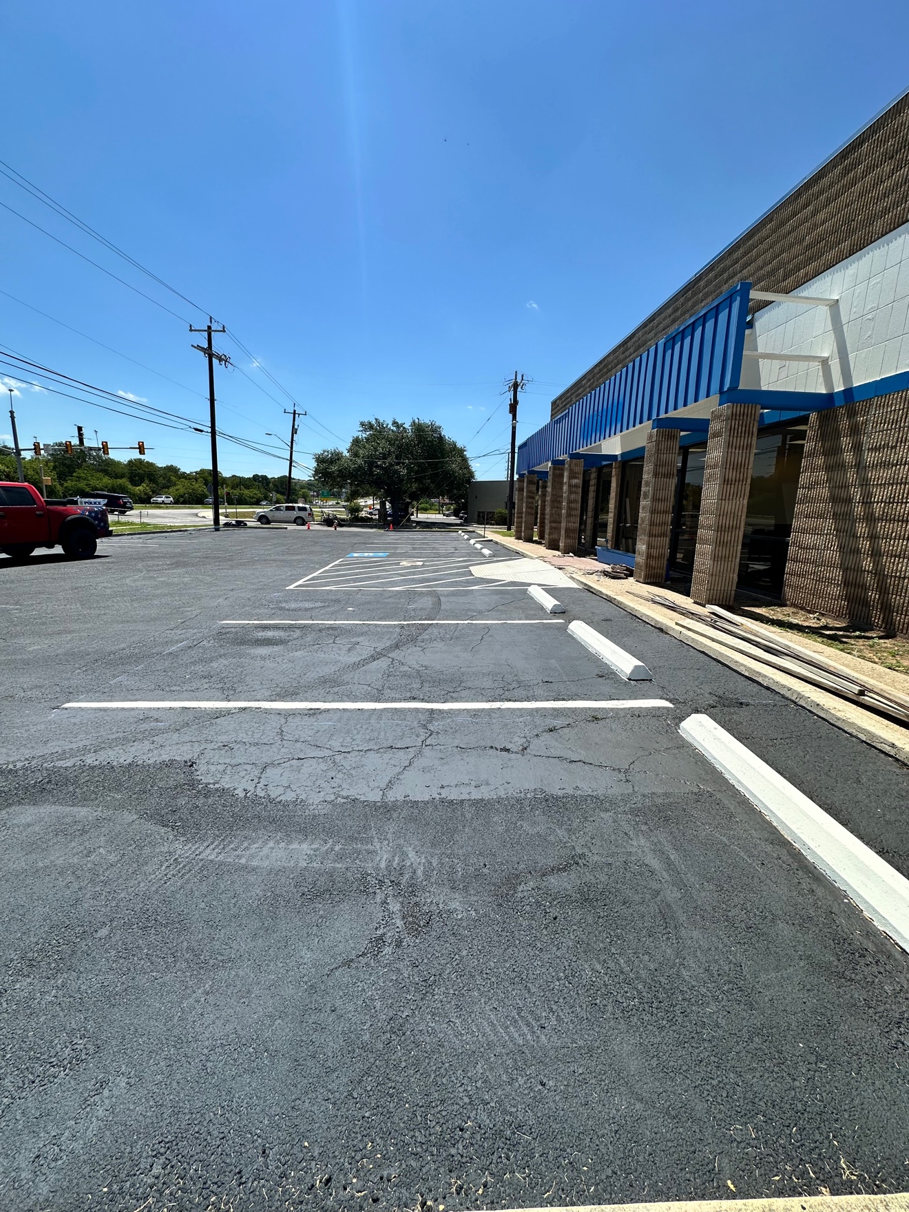 Freshly coated and striped asphalt parking lot in front of a commercial building