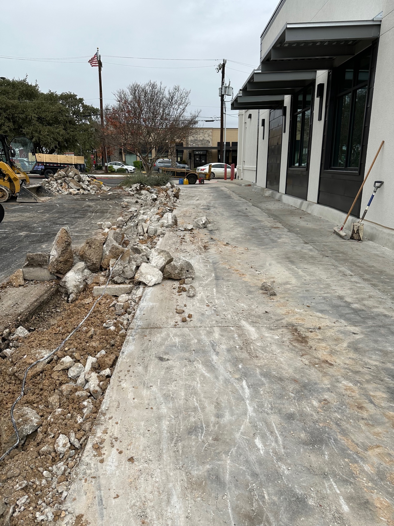 Torn-out old sidewalk and broken concrete piled beside the building on the first job